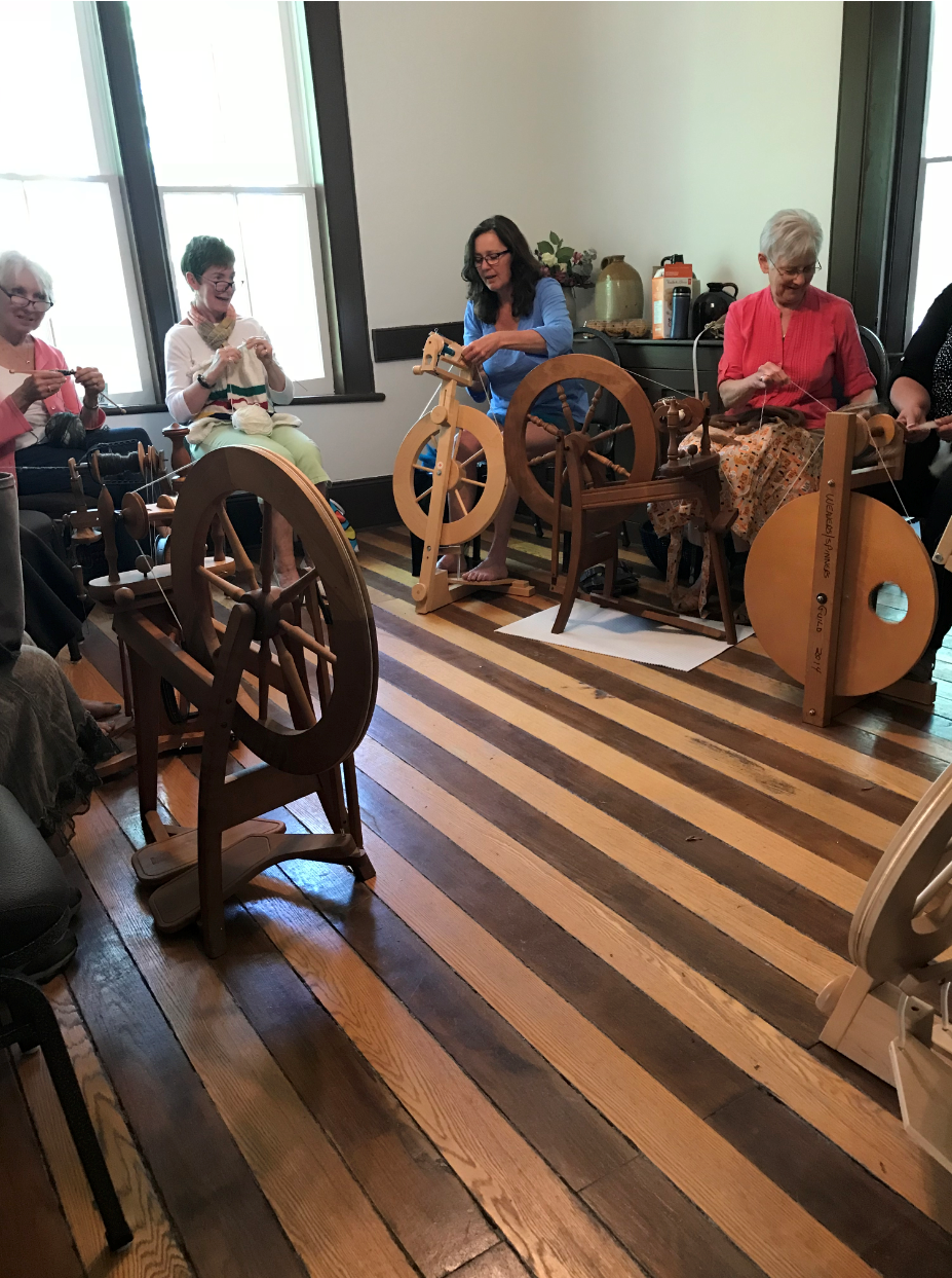 Image of ladies with their spinning wheels 